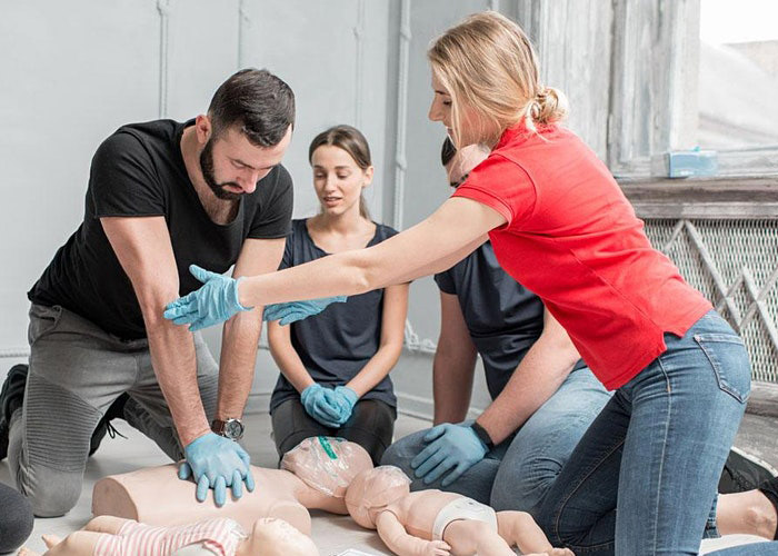 Instructor directing students on how to do CPR on a dummy in Redlands, CA