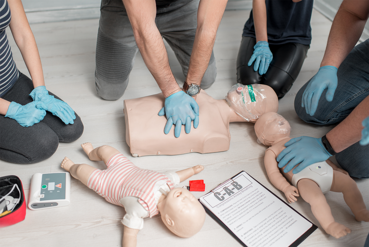 Class performing CPR on adult dummy and baby dummies in Redlands, CA